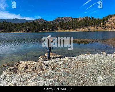 Mann, der am Skaha Lake steht und ein Foto macht, Okanagan, Okanagan Falls, British Columbia, Kanada Stockfoto
