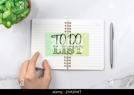 Konzept der To-Do-Liste für das nächste Jahr. Büro-Schreibtisch, weißer Tisch mit silbernem Stift. Draufsicht Stockfoto