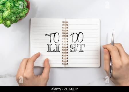 Konzept der To-Do-Liste. Planungsziele für das nächste Jahr. Büro-Schreibtisch, weißer Tisch mit silbernem Stift. Foto von oben Stockfoto