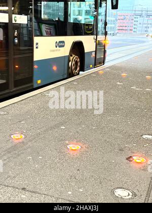Öffentliche Verkehrsmittel Bus an der Bushaltestelle. Es gibt rote Lichter auf dem Boden, die verhindern, dass die Fahrräder auf dem Bürgersteig fahren, wenn es einen Bus gibt. Stockfoto