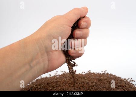 Frau hält braune Leinsamen in der Hand. Nahaufnahme, isoliert. Stockfoto