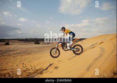 Professioneller Motocross-Fahrer, der den Sandberg hinunterrutscht Stockfoto