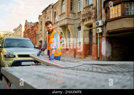 Mann, der den Abschleppwagen für die Fahrzeugbeladung vorbereitet Stockfoto