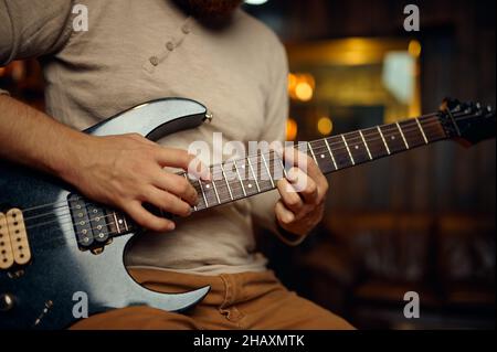 Junger Mann, der E-Gitarre spielt, wurde in einem abgeschnittenen Schuss gedreht Stockfoto