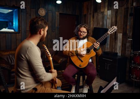 Musiklehrer, der die Eigenschaften des Gitarrenspiels erklärt Stockfoto