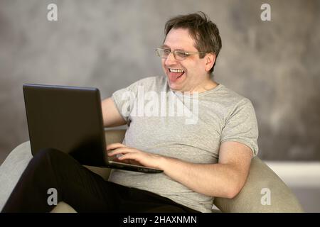 Ein Mann mit 50s Jahren arbeitet von zu Hause aus mit einem Laptop, der mit dem Internet verbunden ist. Stockfoto