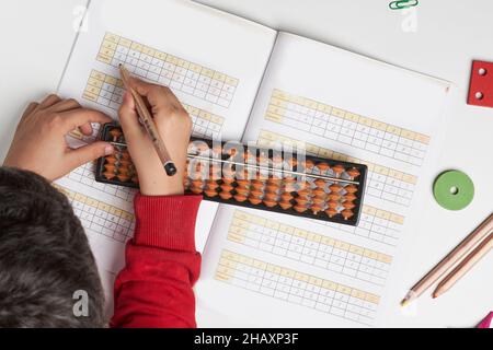 Mentale Mathematik oder mentale Arithmetik. Hand eines kleinen Jungen mit Abakus zur Berechnung. Lernen, Abacus auf mentalen Mathematik-Kursen zu verwenden. Ein Kind, das es tut Stockfoto