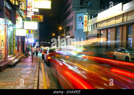 Taxis in einer Linie in Tsim Sha Tsui East in der Nacht mit den leichten Spuren des letzten ankommenden Taxis in Kowloon, Hongkong. Stockfoto