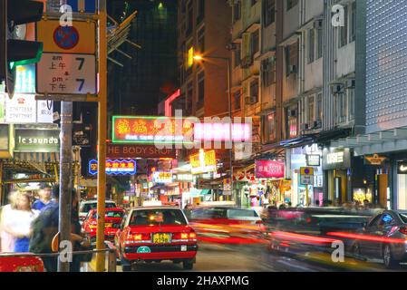 Taxis und Autos mit leichten Wegen bei Nacht in Tsim Sha Tsui East in Kowloon, Hongkong. Stockfoto