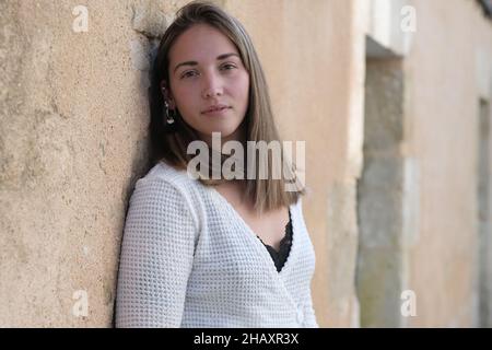 Porträt einer jungen Frau, die an eine Wand gelehnt Stockfoto