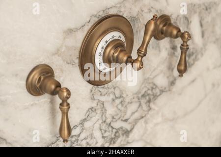 Nahaufnahme von bronzefarbenen Armaturen im Vintage-Stil, die an der Wand mit Marmorfliesen im Badezimmer angebracht sind Stockfoto