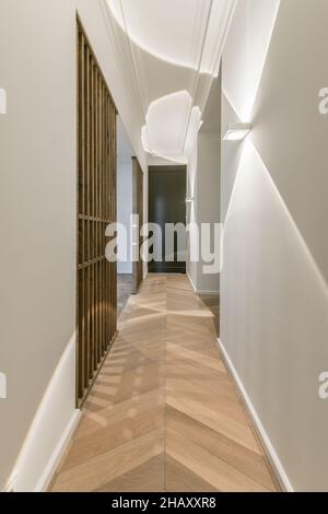 Enger Flur mit grauen Wänden und Parkettboden aus Holz und gewölbter Tür in moderner Wohnung Stockfoto