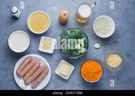 Von oben aus Schüsseln mit Gemüse und Käse und ein Glas Bier auf den Tisch gelegt, bevor Käsesuppe mit Wurst gekocht wird Stockfoto