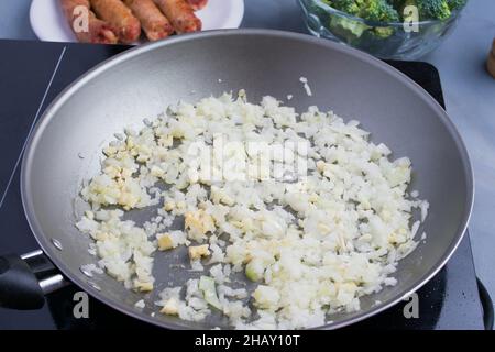 Von oben von frischen gehackten Zwiebeln in Öl Braten in der Pfanne auf Herd in der Küche Stockfoto