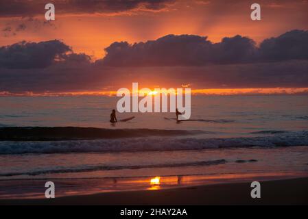 Weit entfernte Silhouette von zwei Personen, Surfen bei Sonnenuntergang, El Palmar Strand, Spanien Stockfoto