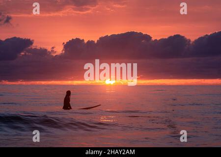 Silhouette einer Frau, die bei Sonnenuntergang surft, El Palmar Strand, Cádiz, Andalusien, Spanien Stockfoto
