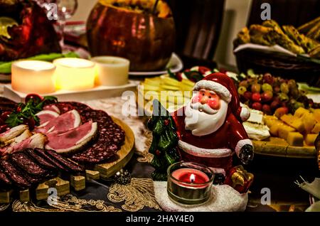Helle festliche Tafel mit verschiedenen Stücken Deli Fleisch und verschiedenen Käsesorten mit Kirschtomaten, Oliven, Nüssen auf rotierenden Holztabletts unter brennenden ca. Stockfoto