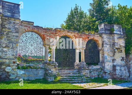 Das gewölbte Tor mit ornamentalem gusseisernem Gitter führt zum Ort der ruinierten armenischen Nikolaikirche, Kamianets-Podilskyi, Ukraine Stockfoto