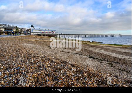 Felixstowe, Suffolk, Großbritannien: Blick auf den Pier von Felixstowe vom Kiesstrand aus. Die Leute laufen entlang der Promenade. Stockfoto