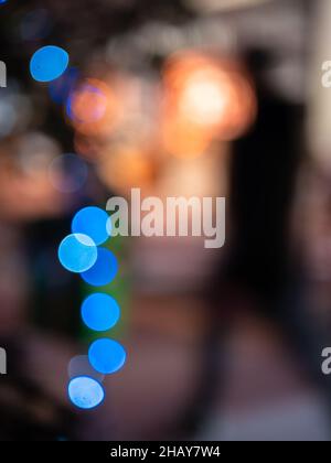 Deliberateljy unscharf Weihnachtslichter - eine Silhouette eines verschwommenen Mannes, der durch die beleuchtete Weihnachtsatmosphäre geht. Stockfoto