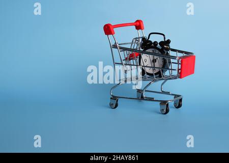 Geschäfts- und Finanzkonzept. Wecker und Einkaufswagen auf blauem Hintergrund. Platz für Text kopieren. Stockfoto