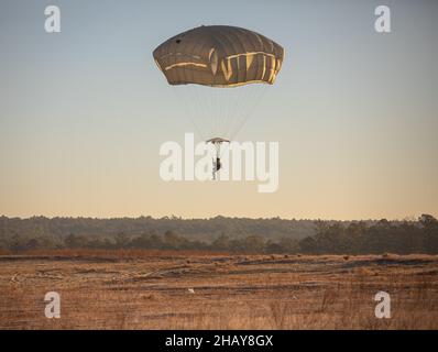 Ein Fallschirmjäger der US-Armee, der der Airborne Division 82nd zugewiesen wurde, bereitet sich auf die Landung während All American Presents from Fallschirmjäger (A2P2) auf Fort Bragg, N.C., 13. Dezember 2021 vor. A2P2 ist eine jährliche Veranstaltung, bei der Fallschirmjäger die Möglichkeit hatten, ein Spielzeug zu spenden, um zu springen und ausländische Sprungflügel zu verdienen. (USA Army Photo von SPC. Jacob Moir). Stockfoto