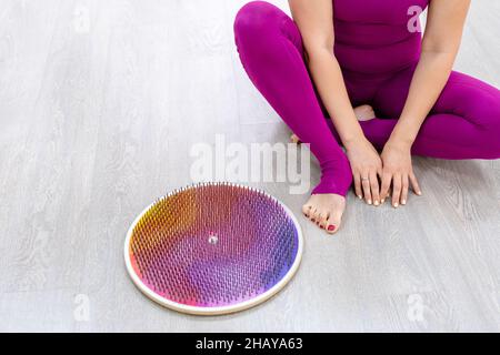 Frau sitzt neben dem Brett mit Nägeln. Yogi-Frau. Die Beine aus der Nähe. Yoga Üben Stockfoto