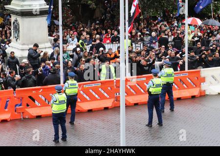 Wellington, Neuseeland. 16. Dezember 2021: Polizeibeamte, die den Eingang zum neuseeländischen Parlament bewachen, beobachten, wie junge Maori-Männer während eines Protests über Covid-19-Impfstoffbevollmächtigungen und Beschränkungen für nicht geimpfte Personen, die Bars, Restaurants und bestimmte andere Orte betreten, einen Haka durchführen. Die Impfraten sind niedriger und die Covid-Infektionen sind bei den Maori- und Pazifikinslandern höher als bei der Allgemeinbevölkerung. Quelle: Lynn Grieveson/Alamy Live News Stockfoto