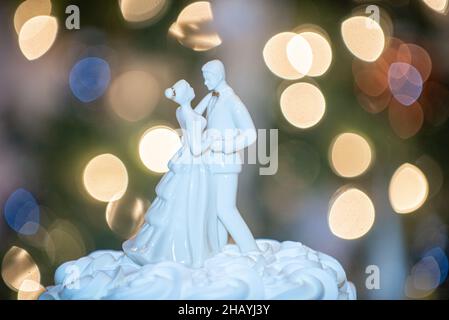 Braut und Bräutigam Kuchen Topper auf vierlagigem Kuchen mit Bokeh-weihnachtsbaum Hintergrund Stockfoto