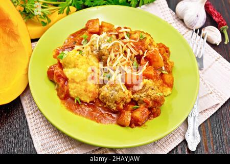 Maisbrei mit Fleischbällchen, Tomatensoße, Knoblauch und Kürbis, bestreut mit Käse und Petersilie auf einem Teller auf einem Küchentuch gegen den Backgro Stockfoto