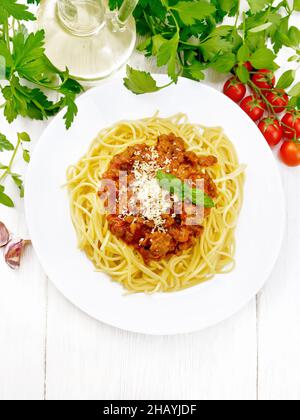 Spaghetti mit Bolognese-Sauce aus Hackfleisch, Tomatensaft, Knoblauch, Wein und Gewürzen mit Käse auf einem Teller, Pflanzenöl, würziges Kraut auf einem Seufzer Stockfoto