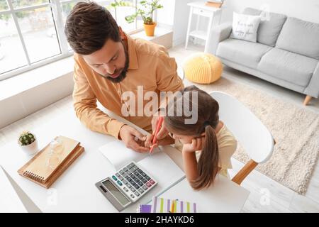 Mann hilft seiner kleinen Tochter, zu Hause Unterricht zu machen Stockfoto