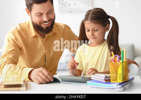 Mann hilft seiner kleinen Tochter, zu Hause Unterricht zu machen Stockfoto