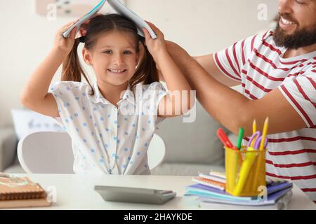 Mann hilft seiner kleinen Tochter, zu Hause Unterricht zu machen Stockfoto