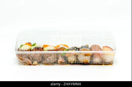 Nahaufnahme verschiedener Sushi-Typen in der zum Mitnehmen abgeräumten Lebensmittelbox, in der langformigen Lebensmittelbox, Vorderansicht Sushi in einer abgeräumten Verpackung auf weißem Hintergrund Stockfoto