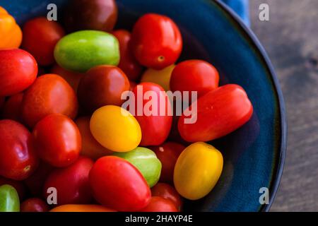 Ansicht von oben auf einer gefalteten Serviette einer Schüssel mit bunten Kirschtomaten Stockfoto