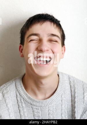 Fröhlicher Teenager, der in der Nähe der Wand im Haus lachte Stockfoto