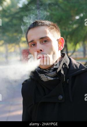 Junger Mann, der im Park raucht Stockfoto