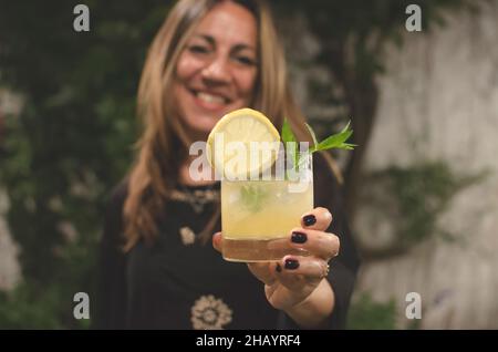 Porträt einer lächelnden Frau mit einem Zitronencocktail Stockfoto