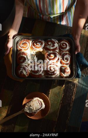 Hausgemachte Zimtbons in der Backform werden aus dem Ofen genommen. Ein Brötchen ist auf dem Teller. Vorderansicht. Stockfoto