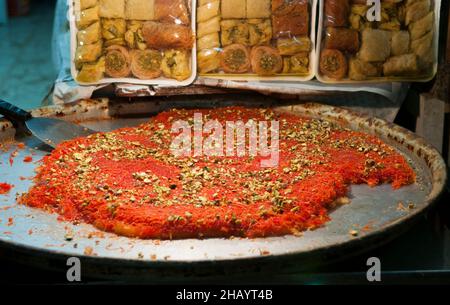 Knafeh ist ein traditionelles Dessert aus dem Nahen Osten, das aus gesponnenen Backwaren namens Kataifi hergestellt wird, die in süßem Zuckersirup getränkt und in der Regel mit Käse übereinander gelegt sind. Stockfoto