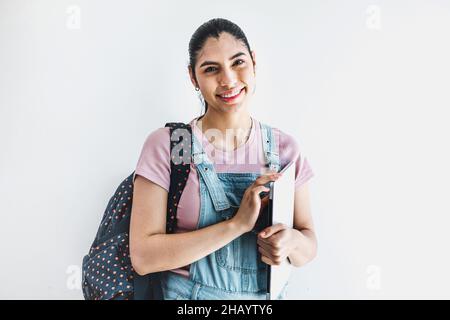 Junge lateinamerikanische Studentin mit Notizbüchern, die mit einer Brille über einem isolierten grauen Hintergrund in Lateinamerika lachen Stockfoto