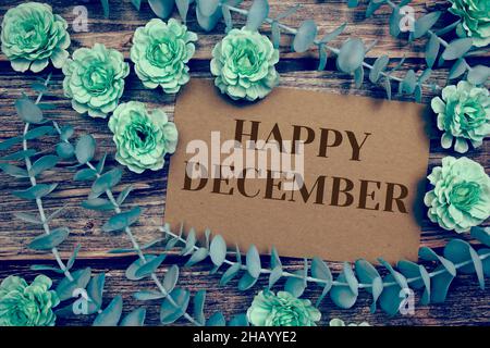 Happy December Typografie Text auf Papier Karte schmücken mit Blumen auf Holzhintergrund Stockfoto