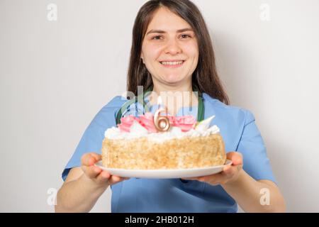 Der Arzt oder die Krankenschwester hält zum Jahrestag der Eröffnung der Klinik einen Geburtstagskuchen mit der Nummer sechs Stockfoto