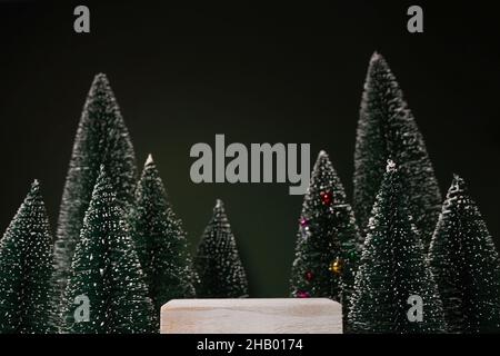 Modell mit Holzpodium auf trendigen dunkelgrünen Hintergrund mit weihnachtsdekoration Bäume. Platz für die produktpräsentation zu weihnachten Stockfoto
