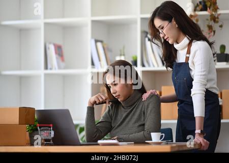 Junge asiatische Frau tröstet ihren Freund mit Problemen im Geschäft. Stockfoto