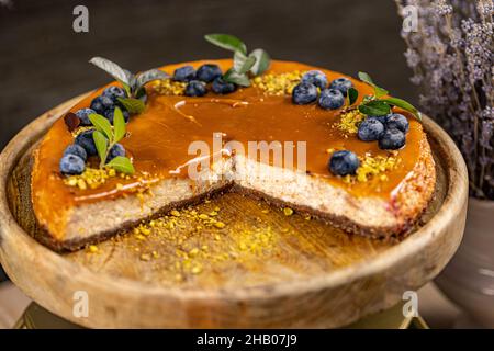 Köstlicher Käsekuchen mit gesalzener Karamellsauce auf der Oberseite, verziert mit Heidelbeere Stockfoto