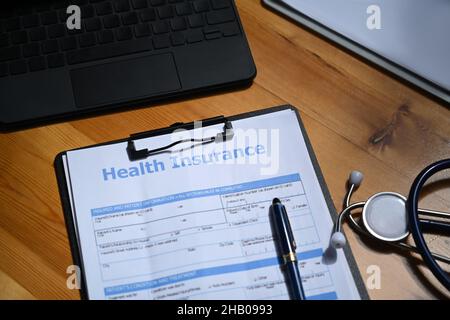 Krankenversicherungsformular und Stethoskop auf Holztisch. Konzept der Krankenversicherung. Stockfoto