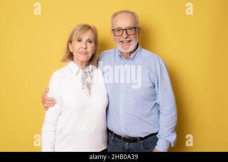 Senior lächelndes Paar posiert zusammen auf gelbem Hintergrund. Stockfoto