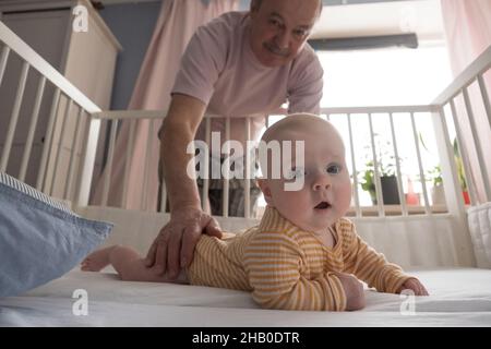 Fröhlicher älterer Großvater, der im Schlafzimmer mit dem Enkel spielt Stockfoto